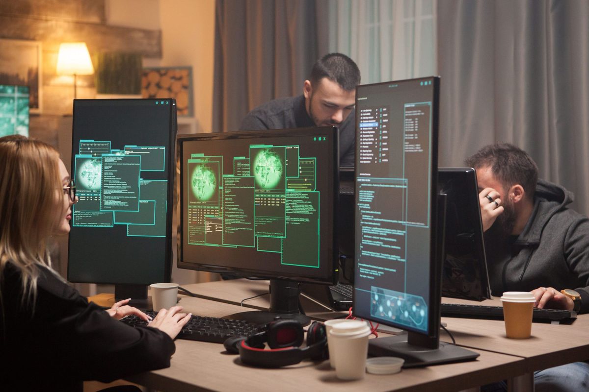 Security specialists reviewing code on multiple monitors
