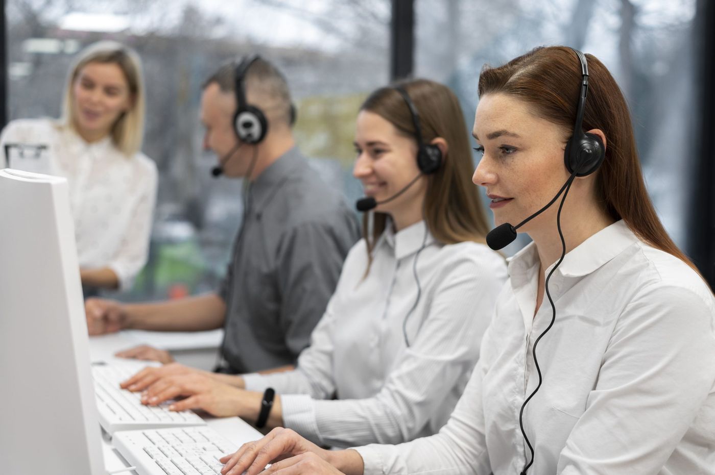 Call centre team working with headsets in a bright office